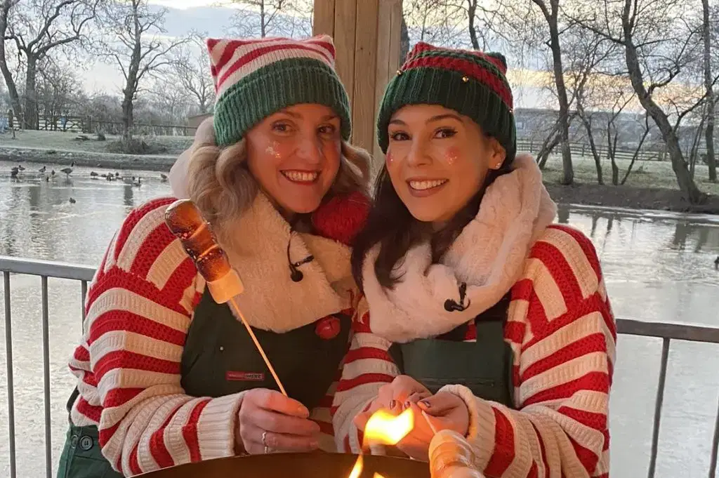 Two Christmas Elves toasting marshmallows by the Monk Park Farm lakeside