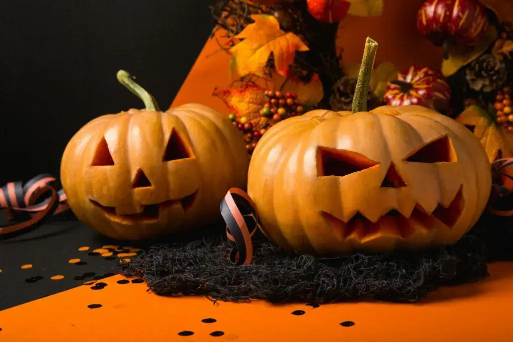Two carved jack-o'-lantern pumpkins with festive Halloween decorations